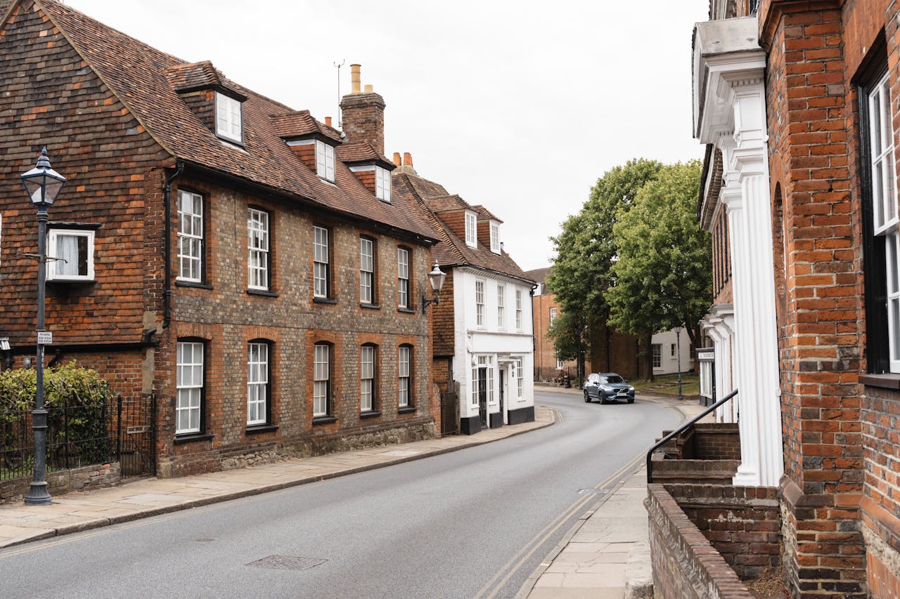 services-03 Scenic view of a quaint English village street with historic brick buildings and greenery.